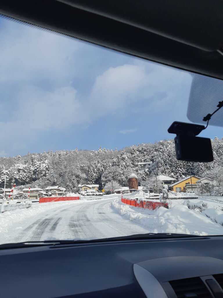 Approaching giant buddha head in snow